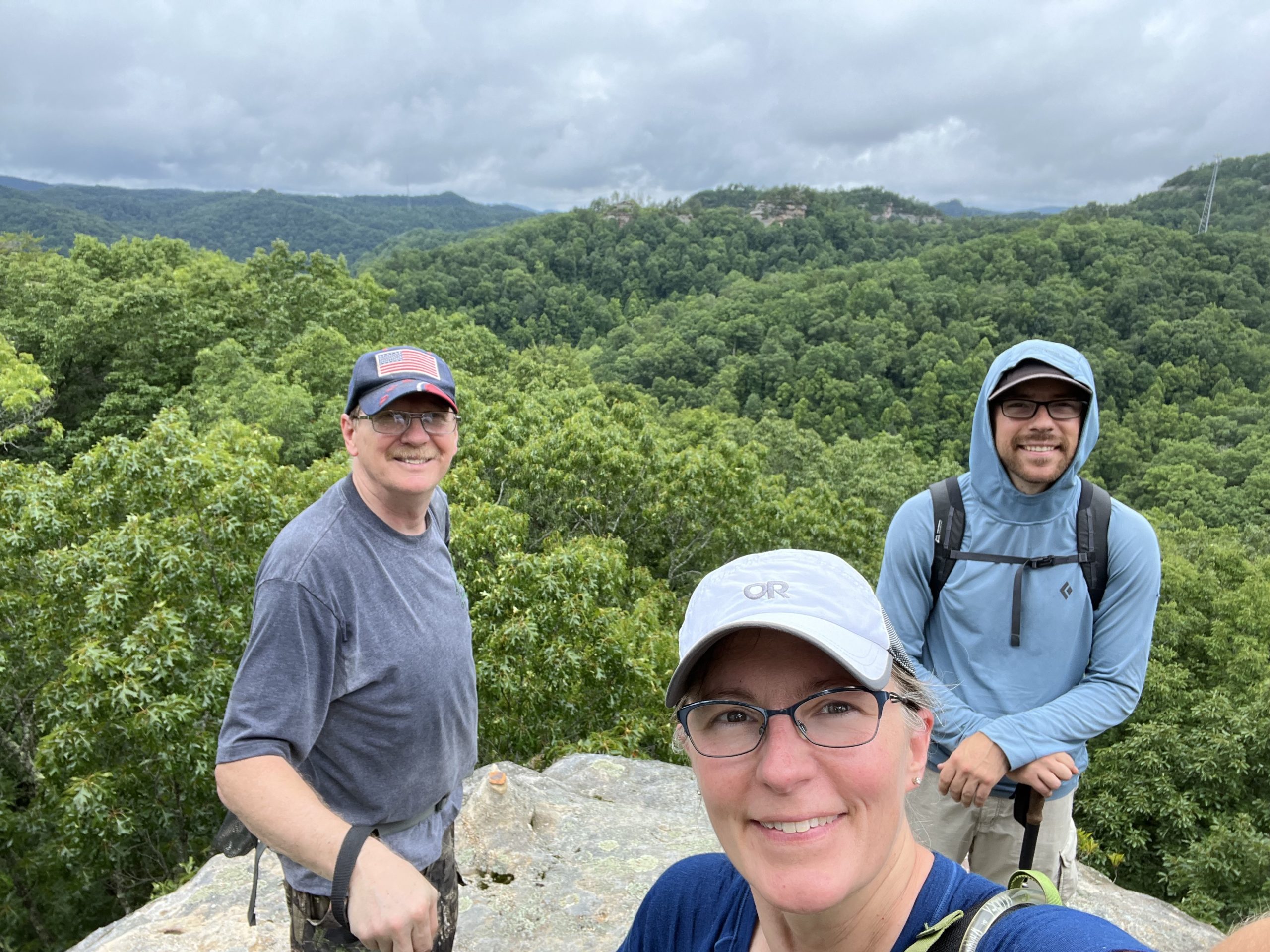 Hikers smiling on a sandstone ridgeline overlook on private property in Daniel Boone National Forest